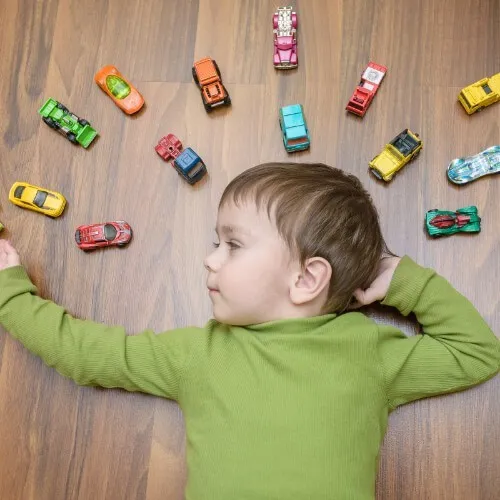 Boy laying on floor with toys | Vic's Carpet & Flooring